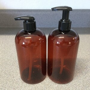 May include: Two amber glass bottles with black pump tops. The bottles are empty and ready to be filled with liquid soap, lotion, or other products.