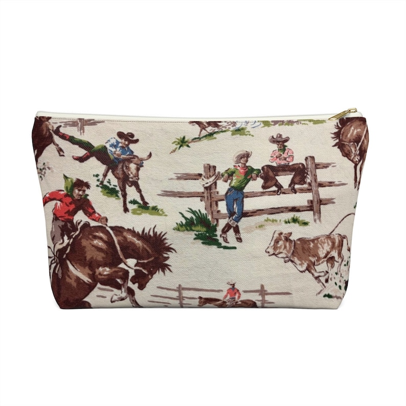 Puede incluir: Una bolsa blanca con cremallera con un patr&oacute;n vintage de vaqueros montando caballos y toros. El patr&oacute;n se repite en toda la bolsa.
