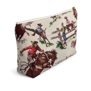 Puede incluir: Una bolsa blanca con cremallera con un patr&oacute;n vintage de vaqueros montando caballos y toros. El patr&oacute;n est&aacute; en tonos de marr&oacute;n, rojo, verde y azul.