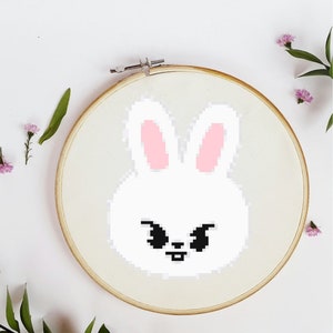 May include: A white bunny with pink ears and black eyes is embroidered on a white fabric stretched over a wooden embroidery hoop.