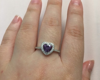 May include: A silver ring featuring a heart-shaped purple gemstone with a halo of smaller clear gemstones.