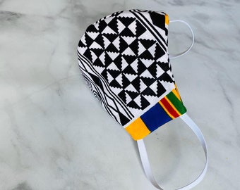 May include: A black and white patterned face mask with a yellow, blue, green, and red trim. The mask has white elastic ear loops.
