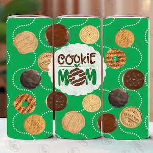 May include: A green tumbler featuring a pattern of various cookies and white dotted lines. The center of the tumbler has the words "Cookie Mom" with a cookie design. The cookies are in shades of brown and tan.