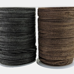 May include: Two spools of leather cord, one black and one brown. The cord is wound tightly around the spools.