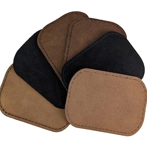 May include: A collection of rectangular suede patches with rounded corners, featuring visible stitching along the edges. The set includes multiple pieces in varying shades of brown, tan, and black, arranged in an overlapping, fan-like formation.