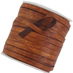 May include: A roll of brown leather strips. The leather has a textured, distressed appearance with variations in colour, ranging from light to dark brown. The strips are neatly wound around a white plastic core, with a dark brown strip extending from the roll.