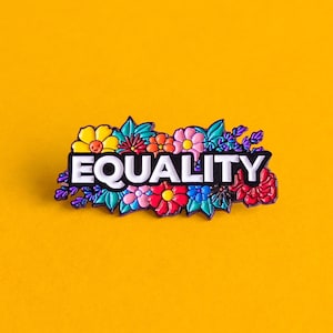 May include: A colourful enamel pin with a floral design and the word "EQUALITY" in white letters.