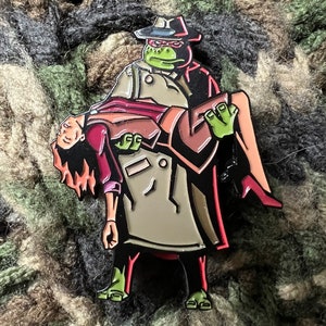 Puede incluir: Una tortuga verde con un abrigo marrón y un sombrero rojo fedora lleva a una mujer con un vestido rojo y marrón. La tortuga tiene un pañuelo rojo alrededor del cuello y una cara verde. La mujer tiene el pelo rojo y lleva zapatos rojos.