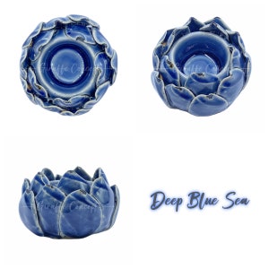 May include: A deep blue ceramic candle holder, shaped like a lotus flower. The glossy finish candle holder has a blooming flower design. The text "Deep Blue Sea" is written in a cursive font.