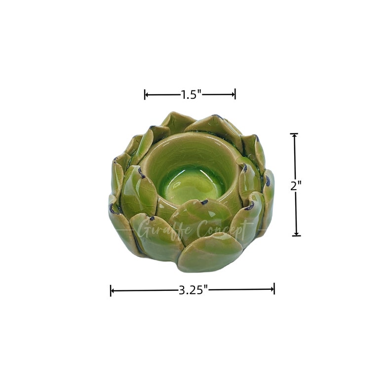 May include: A green ceramic artichoke-shaped candle holder. The candle holder is 8.26 cm wide, 5.08 cm tall, and 3.81 cm deep. The interior is a glossy green, and the exterior has a textured, leaf-like design. The text "Giraffe Concept" is visible.