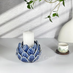 May include: Blue ceramic candle holder shaped like an artichoke with a white candle inside.
