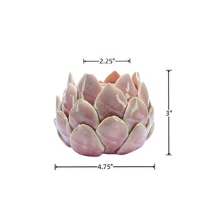 May include: A pink ceramic planter shaped like a flower with 4.75 inches in diameter and 3 inches in height.