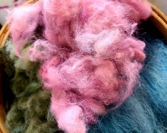 May include: A basket filled with three different colors of wool roving: pink, green, and blue.