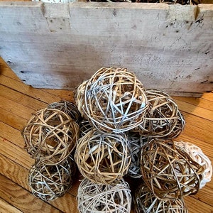 May include: A group of woven sphere ornaments in various shades of brown and white. The spheres are made of natural materials and have a rustic, farmhouse aesthetic.