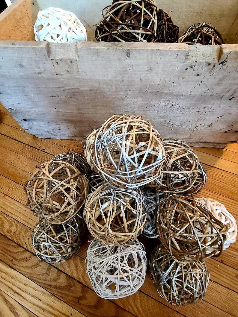 May include: A group of woven sphere ornaments in various shades of brown and white. The spheres are made of natural materials and have a rustic, farmhouse aesthetic.