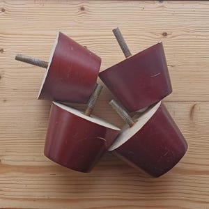 May include: Four dark red wooden furniture legs with metal screws. The legs are round and have a slightly tapered shape.