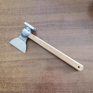 Könnte beinhalten: Ein silberner Fleischhammer mit einem Holzstiel. Der Hammer hat einen strukturierten Kopf zum Zartmachen von Fleisch.
