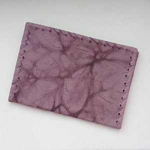 May include: A small, rectangular, purple leather wallet with a stitched edge.