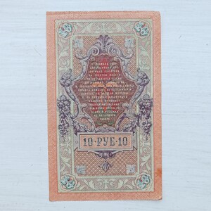 Op de afbeelding: Een rechthoekig vintage Russisch bankbiljet van 10 roebel met ingewikkelde ornamenten, bloemmotieven en cyrillische tekst in zwarte en rode inkt op een perzikkleurige achtergrond, met het getal 10 weergegeven in de hoeken van het biljet.
