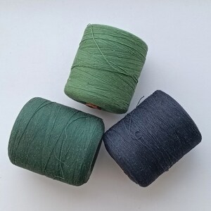 May include: Three spools of thread, one dark green, one light green, and one black.