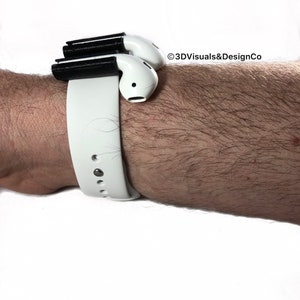 K&ouml;nnte beinhalten: Ein wei&szlig;es Armband mit einem schwarzen 3D-gedruckten Aufsatz zum Halten von drahtlosen Ohrh&ouml;rern. Der Text "&copy;3DVisuals&DesignCo" ist im Bild sichtbar.