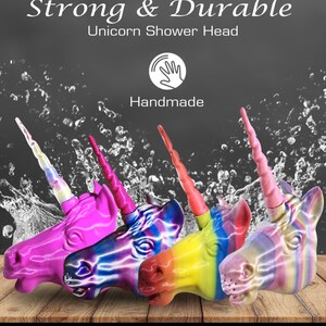 May include: Four colorful unicorn shower heads with a rainbow, pink, yellow, and purple design. The shower heads are made of a durable material and are handmade. The text "Strong & Durable" and "Unicorn Shower Head" is visible at the top of the image. The text "Handmade" is visible below the image of a hand.