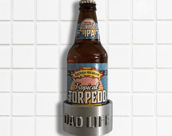 以下が含まれることがあります： 前面に「Dad Life」と刻まれた銀色の金属製のボトルオープナー。ボトルオープナーには、シエラネバダトロピカルトルピードIPAのボトルが入っています。