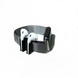 K&ouml;nnte beinhalten: Eine schwarze und silberne Apple Watch mit einem Metallband und einem schwarzen 3D-gedruckten Halter f&uuml;r AirPods.