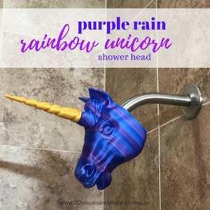 May include: A purple and blue unicorn shower head with a gold horn. The shower head is attached to a silver shower arm. The text "purple rain rainbow unicorn shower head" is visible at the top of the image.