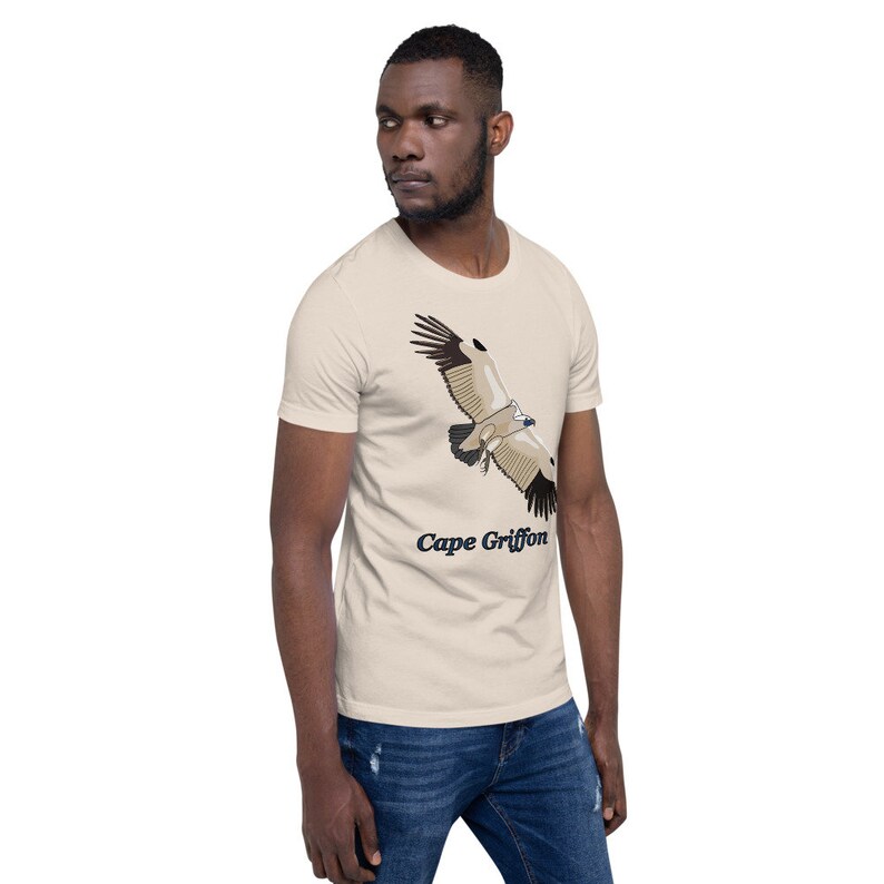 May include: A beige t-shirt featuring a graphic of a Cape Griffon vulture in flight. The text "Cape Griffon" is printed below the bird.