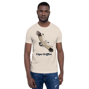 May include: A beige t-shirt featuring a graphic of a Cape Griffon vulture in flight. The text "Cape Griffon" is printed below the bird.