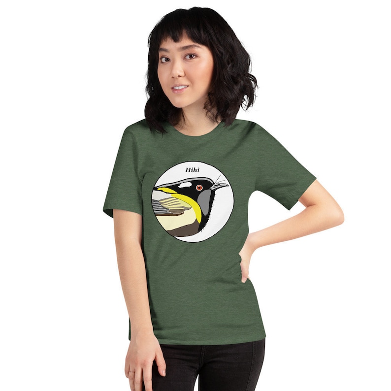 May include: A green short-sleeved t-shirt with a white circle featuring a colourful illustration of a bird with the word "Hihi" above it.