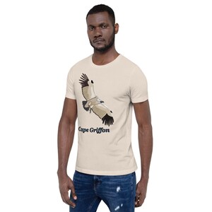 May include: A beige t-shirt featuring a graphic of a Cape Griffon vulture in flight. The text "Cape Griffon" is printed below the bird.