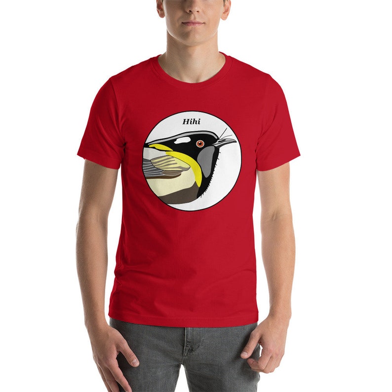 May include: Red short-sleeved t-shirt with a white circle graphic featuring a black and yellow bird with the word "Hihi" above it.