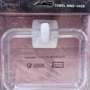 May include: A clear, rectangular towel ring with a white ceramic clip. The packaging reads "TOWEL RING - 0426" and "CERAMIC CLIP-ON OR FASTICK". The product is from "LENAPE" and "MADE IN USA".