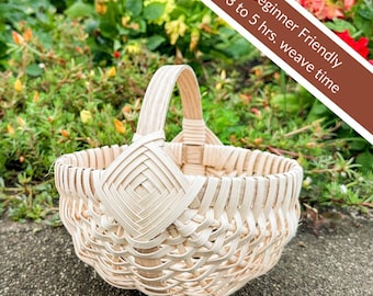 May include: A small, light-colored woven basket with a handle. The basket has a diamond-shaped design on the front and is surrounded by greenery. Text on the image reads "Beginner Friendly 3 to 5 hrs. weave time."