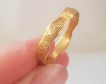 May include: A gold ring with a wavy, textured band.
