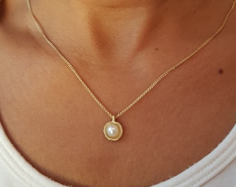 May include: A gold chain necklace with a small pendant featuring a single pearl in a gold setting.