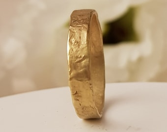 May include: A gold band ring with a textured surface.
