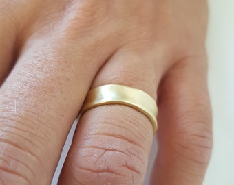 May include: A simple gold wedding band with a brushed finish.