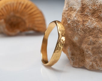 May include: A gold ring with a hammered texture. The ring is thick and has a rounded shape.