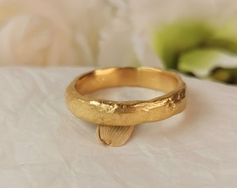 May include: A simple gold band ring with a textured, hammered finish.