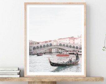 May include: A black gondola with a gondolier rowing on a canal in Venice, Italy. The Rialto Bridge is in the background.