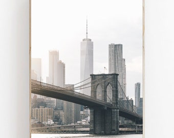 Puede incluir: Una fotografía en blanco y negro del puente de Brooklyn en la ciudad de Nueva York. El puente está en primer plano, con el horizonte de la ciudad en el fondo. La foto está tomada desde un ángulo bajo, lo que da al espectador una idea de la escala del puente.