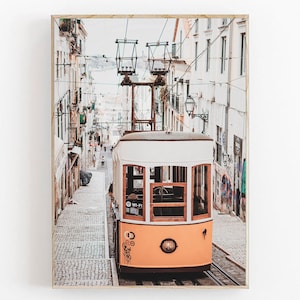 May include: A yellow and white vintage tram travels up a cobblestone street in a European city. The tram has a sign that says "Wi-Fi" on the side. The street is lined with buildings on both sides.