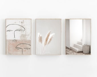Peut inclure: Trois impressions encadrées avec une esthétique minimaliste. L'impression de gauche présente un visage abstrait beige et rose avec des dessins au trait noirs. L'impression centrale présente un groupe de pampas séchées sur un fond beige. L'impression de droite montre un escalier blanc avec un panier en osier sur la marche inférieure.