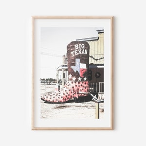 May include: A large, pink and white cowboy boot with a brown top and the words "Big Texan" on it. The boot is in front of a building with a Texas flag on it.