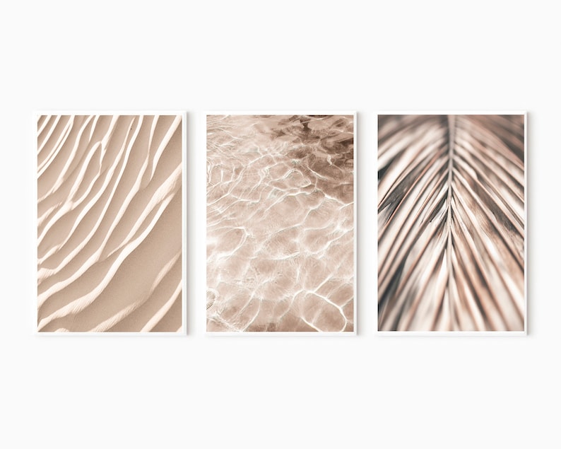 May include: A set of three abstract prints featuring close-up textures of sand, water, and a palm leaf. The prints are in shades of beige and brown.