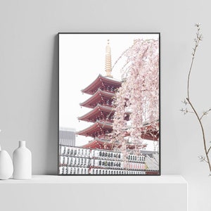 May include: A framed photograph of a red pagoda with a cherry blossom tree in the foreground. The pagoda is a traditional Japanese architectural structure with multiple tiers. The cherry blossom tree is in full bloom, with delicate pink flowers.