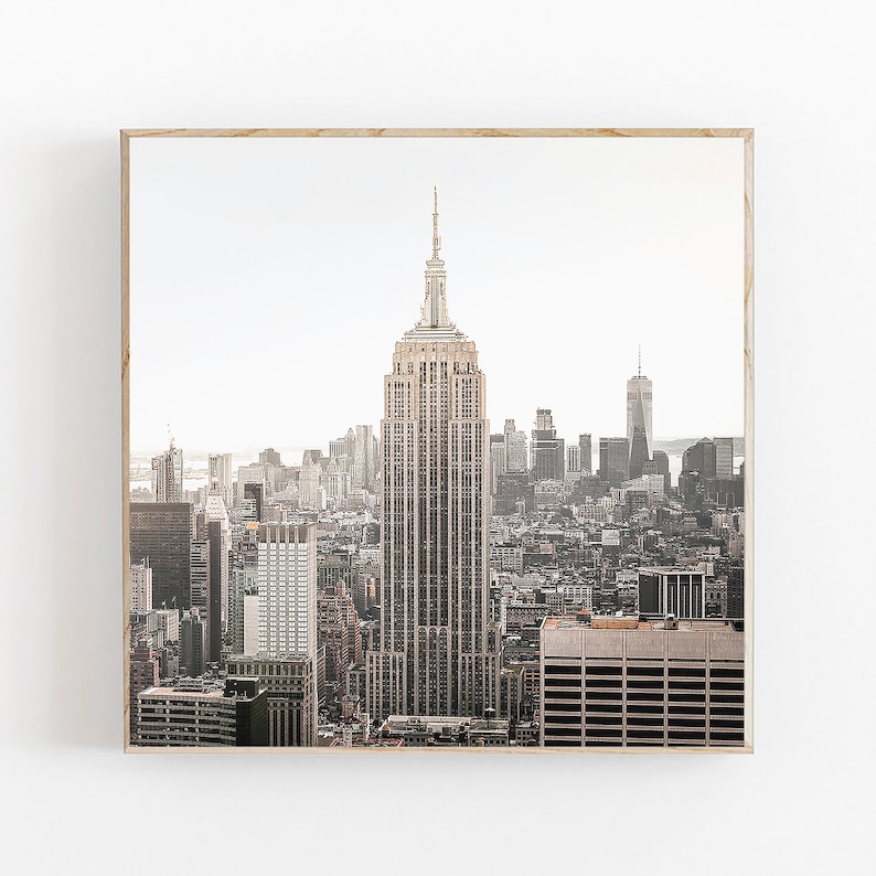 May include: A panoramic view of the New York City skyline with the Empire State Building in the center. The city is bathed in a warm, golden light, creating a sense of tranquility and grandeur.